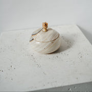 Marble-patterned container with wooden handle on a textured surface