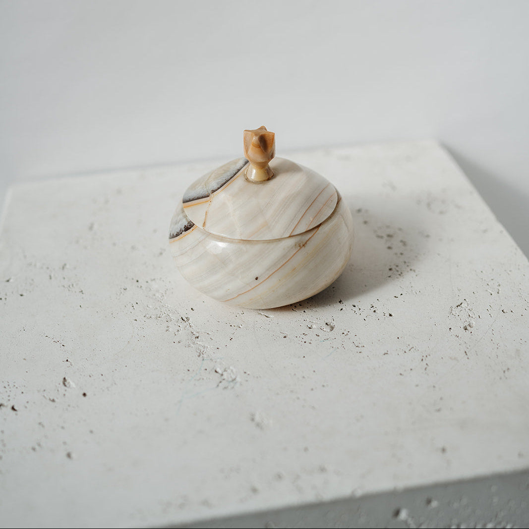 Marble-patterned container with wooden handle on a textured surface