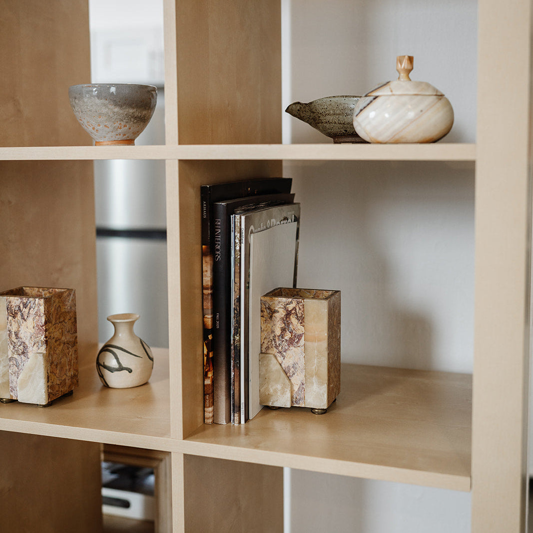 Wooden bookshelf with decorative items including books, a vase, and stone bookends 